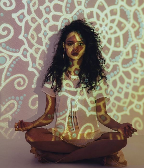 Woman in a calm yoga pose surrounded by vibrant colors.